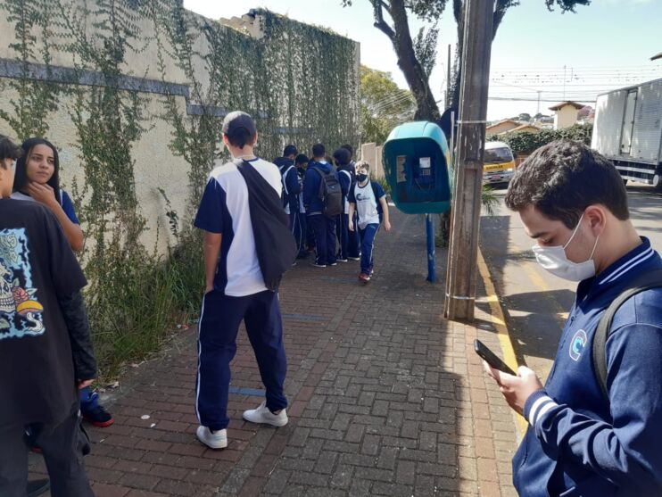 Estudante Flávio Pereira de Miranda usa celular ao lado de orelhão em Apucarana