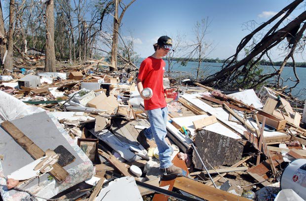 Garoto caminha sobre restos de casa destruída por tornado no condado de Warren