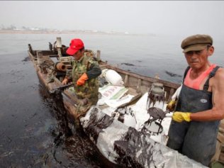 Fotografia divulgada pelo Greenpeace mostra as tentativas rudimentares de coletar o petróleo em Dalian