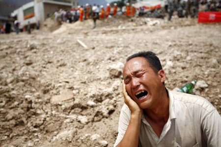 Homem chora por parente desaparecido após deslizamento de terra no noroeste da China; mortos na tragédia passam de 700, dizem fontes oficiais