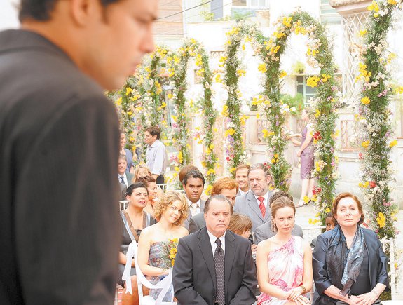 Na primeira fila, ao lado de Totó, Clara observa Danilo que está no altar como um dos padrinhos do casamento