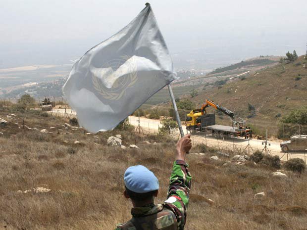 Funcionário da missão da ONU levanta bandeira em região de patrulha israelense na fronteira com o Líbano