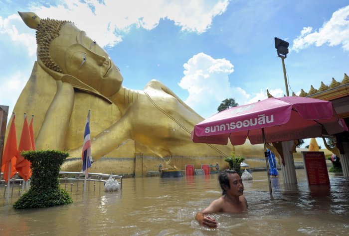 Homem caminha entre ruas inundadas perto de um tempo budista em Ayutthaya, na Tailândia