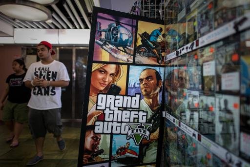 Um homem perto de um painel do jogo "Grand Theft Auto V", em Hong Kong (AFP Photo, PHILIPPE LOPEZ)