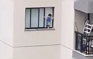 Criança é flagrada pendurada em janela de edifício