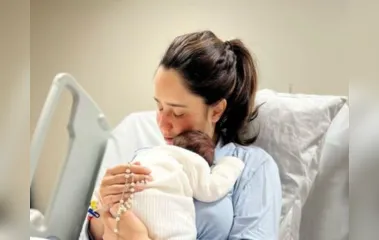 Fernanda aparece na cama da maternidade com o menino no colo, abraçando-o